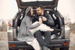 Cute couple in a field. Man in a black jacket. Family sitting on a trank.