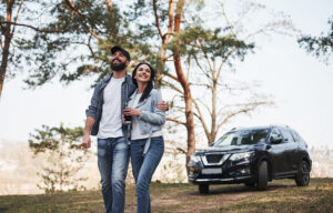 Peace and quiet. Embracing and enjoying the nature. Couple have arrived to the forest on their brand new black car.